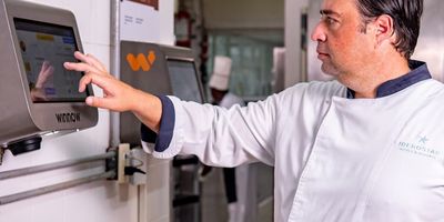 Chef touching a wall-mounted tablet to manage restaurant business