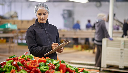 A woman in a factory, holding a clipboard, overseeing operations and ensuring efficiency.